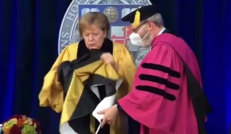 Как это носят? Меркель пыталась надеть почётную ленту выпускника — вышло смешно (ВИДЕО)
